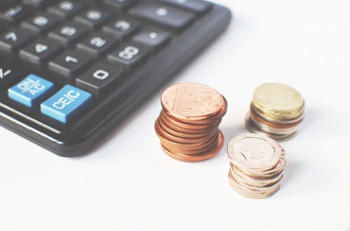 Coins kept beside a calculator to reduce cost per lead